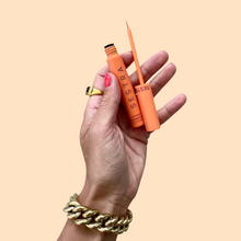 Load image into Gallery viewer, 1 orange tube of eyelash growth serum being held up by a feminine hand
